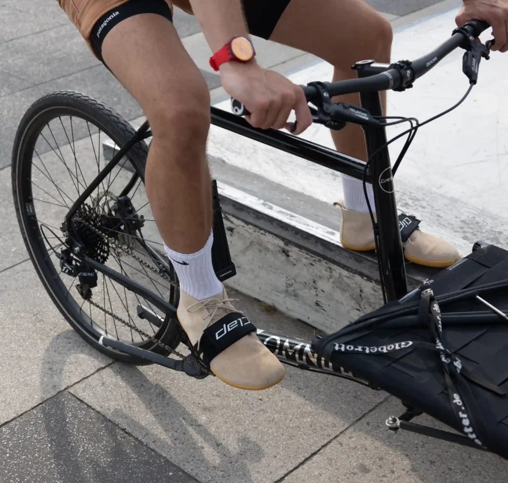 Radfahrer in sommerlicher Kleidung mit Barfußschuhen in Klickpedale auf Fahrrad eingeklickt