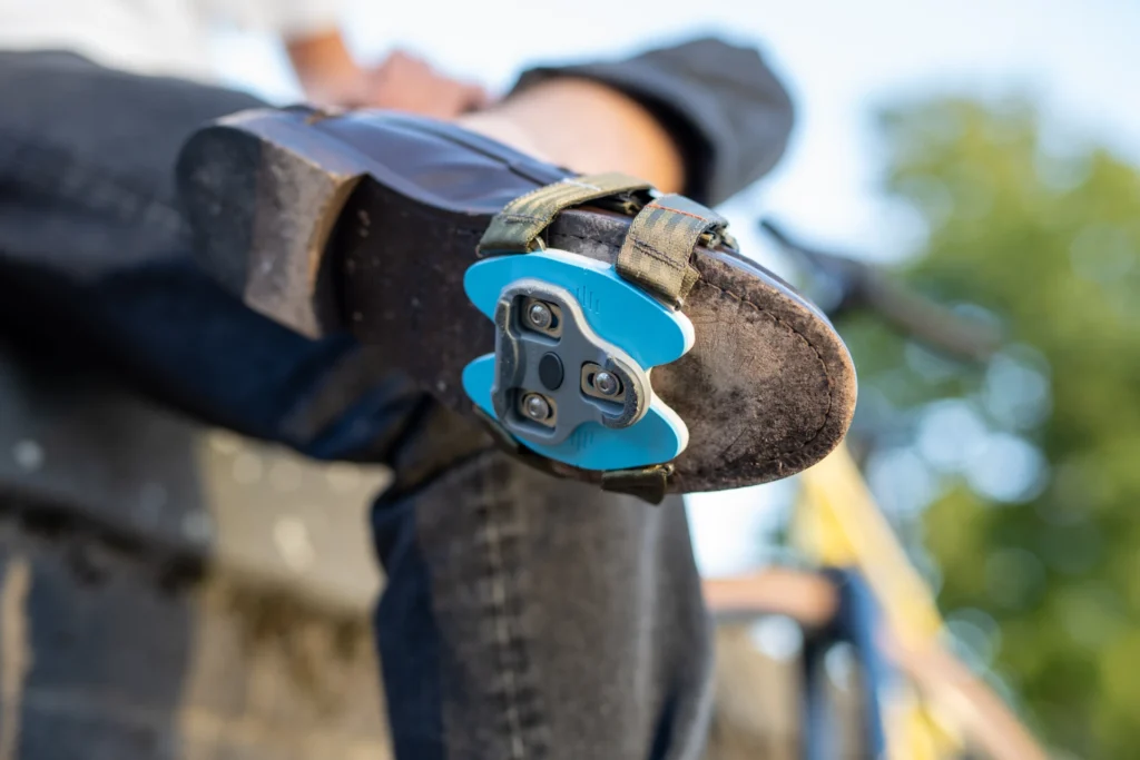 Adapter mit blauer Grundplatte verwandelt Straßenschuh in Fahrradschuh mit 3-Loch-Klickfunktion